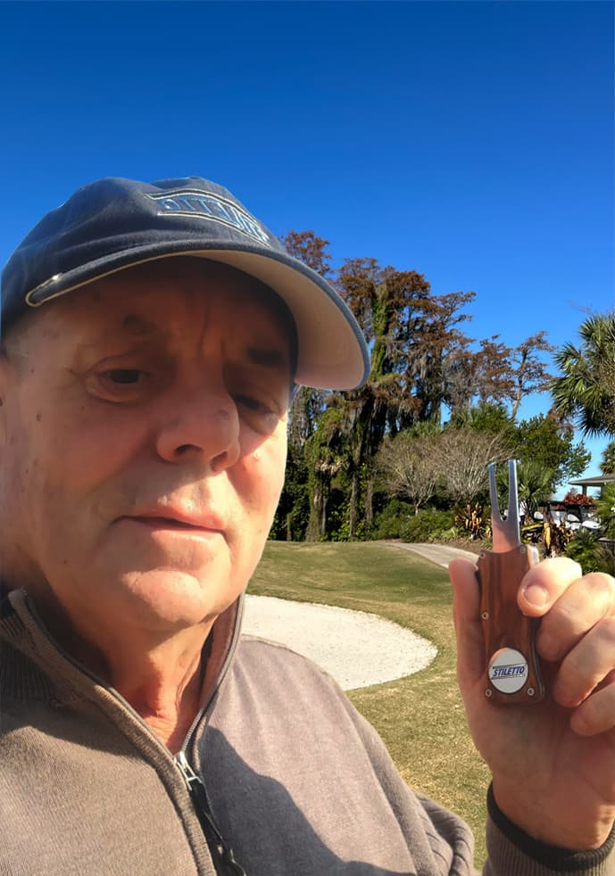 Jim Rourke, founder of Stiletto Golf, holding a Stiletto ball mark repair tool on a golf course