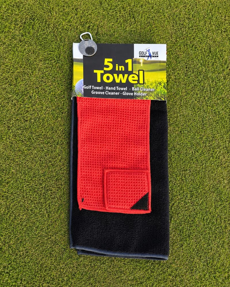 The Golf Vue 5-in-1 golf towel in red and black with its packaging tag, laid out on a putting green